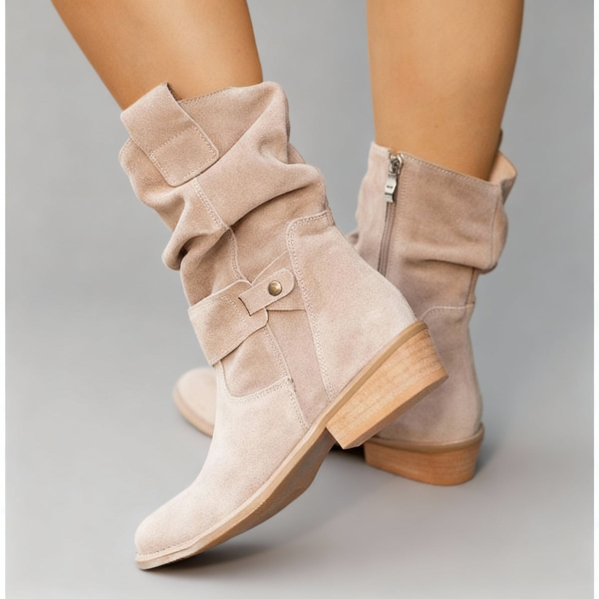 Beige suede slouchy ankle boots with buckle details and low block heels.
