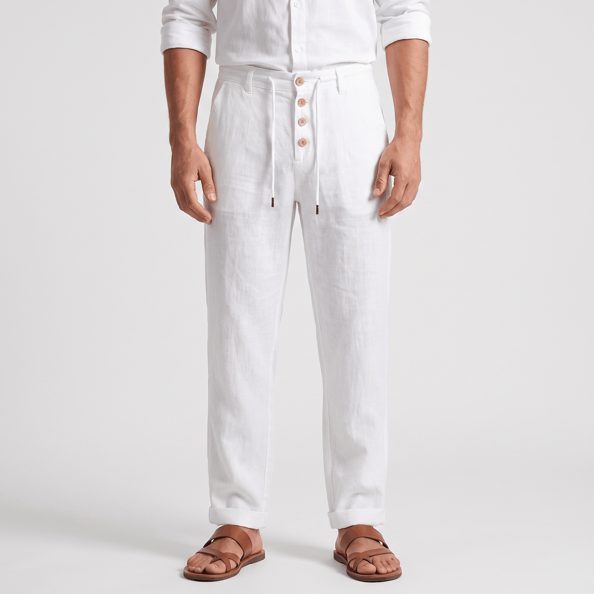 Men's white linen drawstring pants with a relaxed straight-leg fit, button-front detail, elastic waistband, and side pockets.