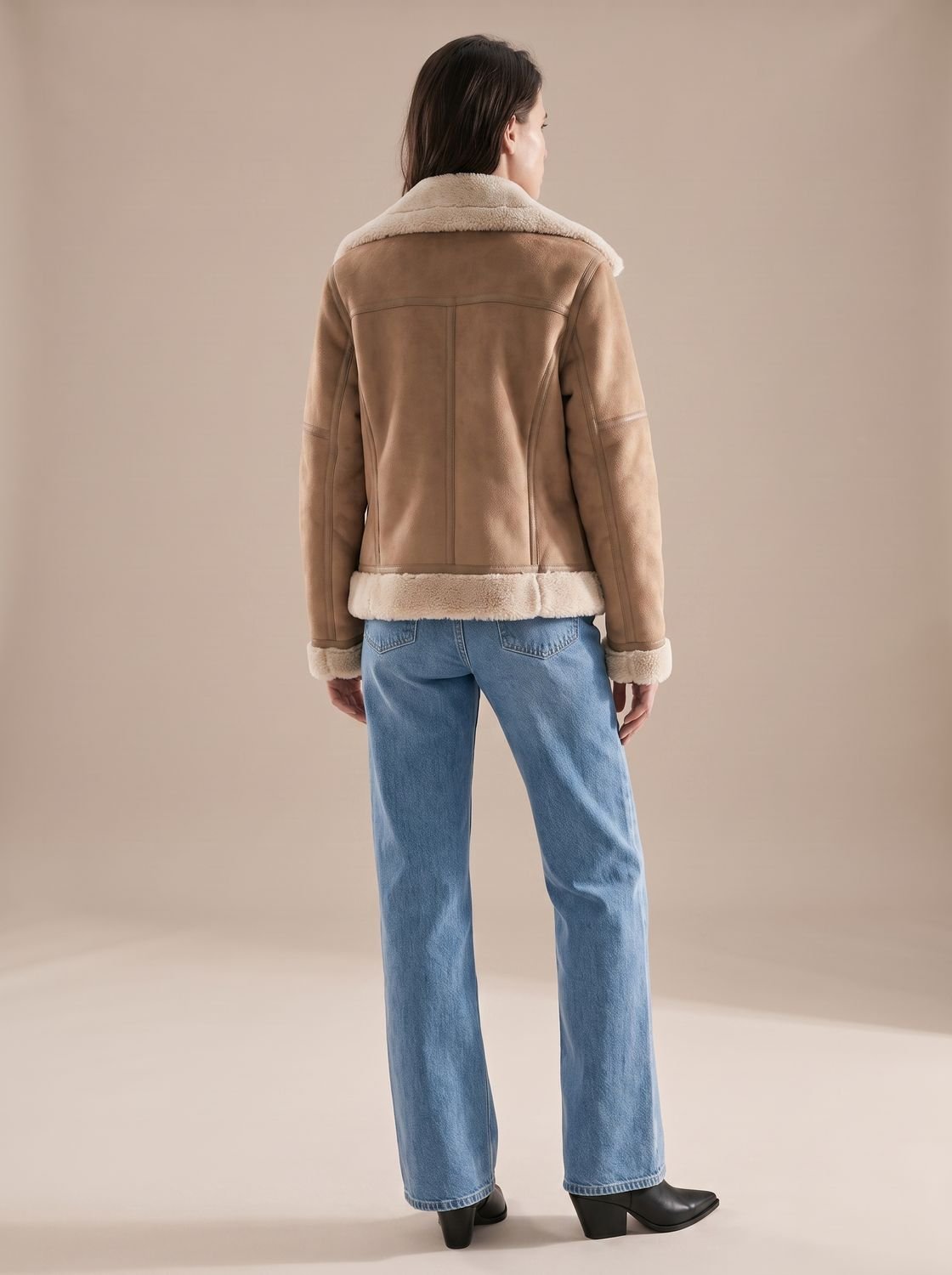 Taupe belted shearling aviator jacket worn by a woman, back view with plush lining and structured fit