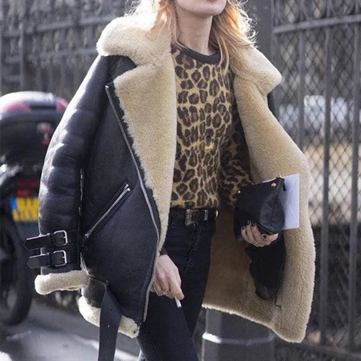 Black shearling aviator jacket for women worn by a model, featuring plush lining and wide collar