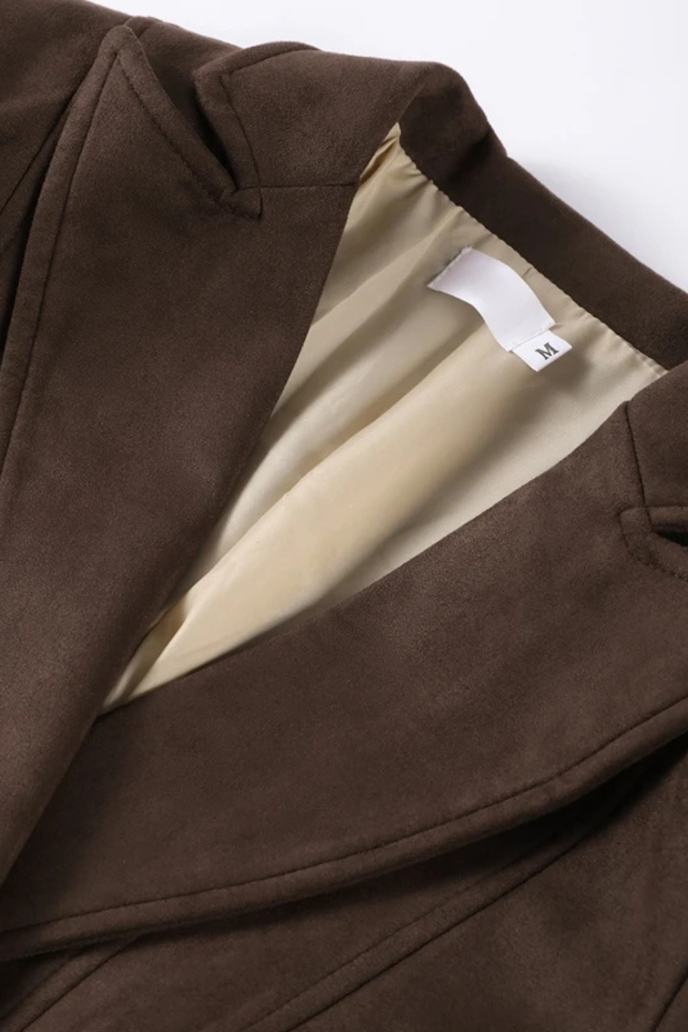 Close-up of a dark brown suede jacket showing the soft inner lining and leather exterior