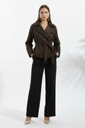 A woman wearing a dark brown belted suede jacket with a relaxed fit and turn-down collar