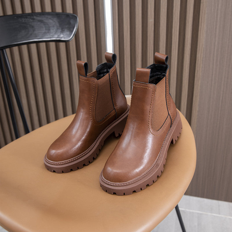 Brown leather block heel Chelsea boots for women on a round stool, showing the deep lug tread
