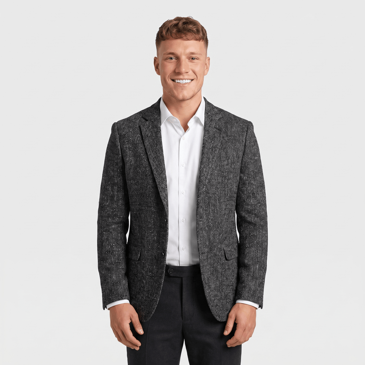 Front view of a man wearing a charcoal gray tweed blazer with a notched lapel, button closure, flap pockets, and tailored silhouette.