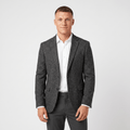 Man wearing a charcoal gray tweed blazer with a notched lapel, two-button closure, flap pockets, and tailored fit over a white dress shirt and dark trousers.