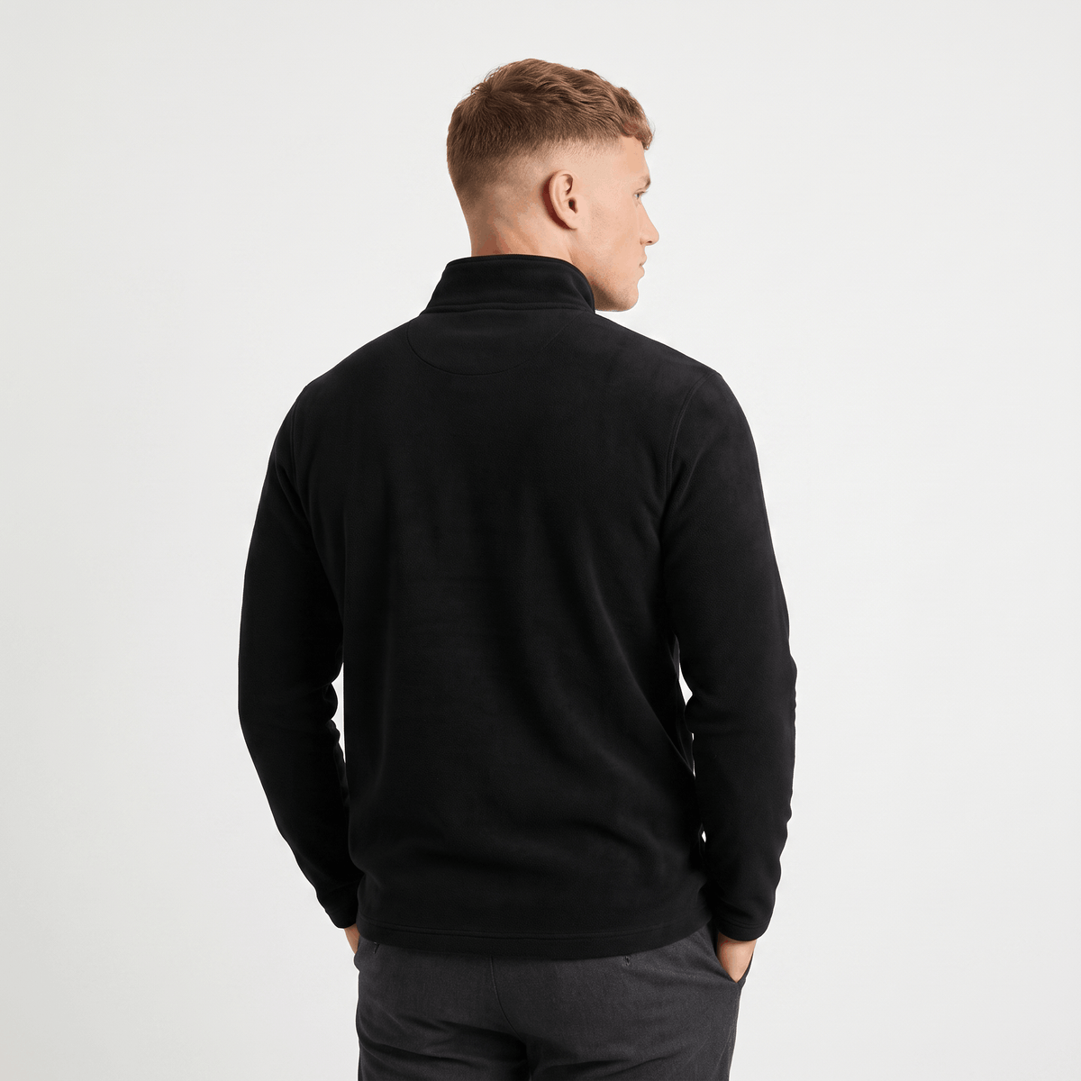Back view of a men's black quarter-zip knit sweater with a stand collar and ribbed trim.