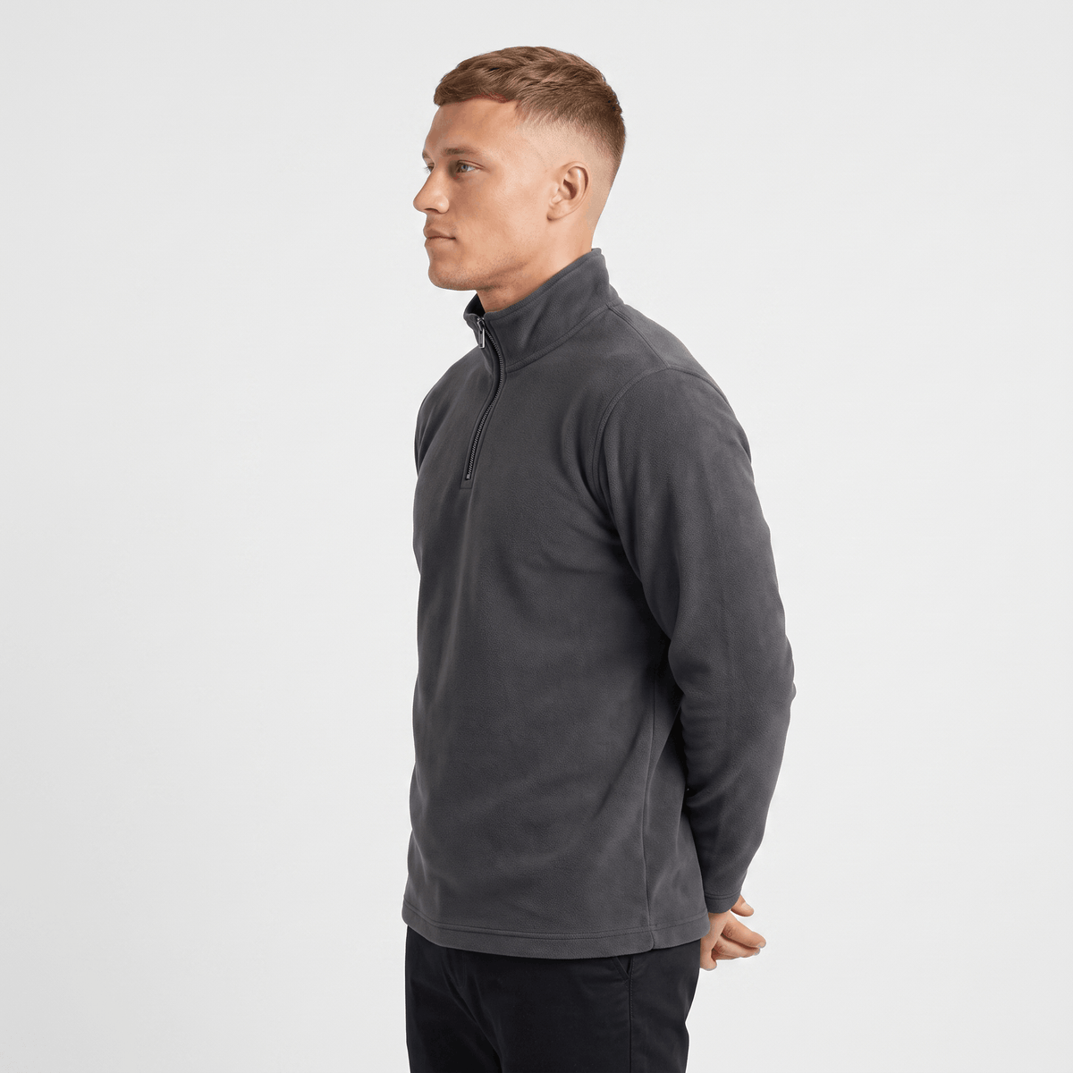 Side view of a man wearing a charcoal gray quarter-zip sweater with a stand collar and ribbed cuffs.