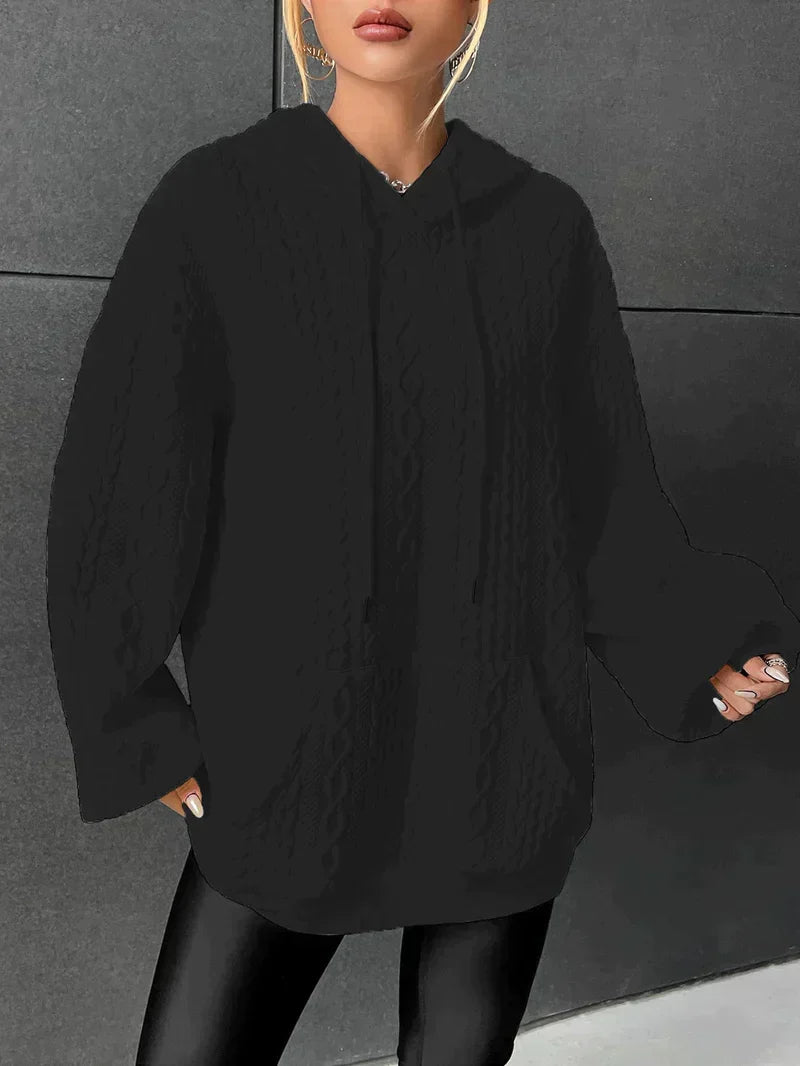 Black oversized cable knit hoodie for women with a kangaroo pocket, drawstring hood, and long sleeves