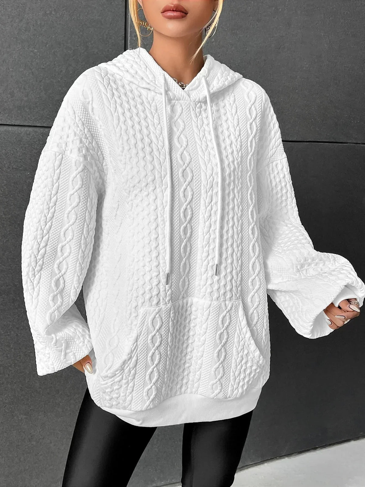White oversized cable knit hoodie for women with a kangaroo pocket, drawstring hood, long sleeves, and textured knit pattern