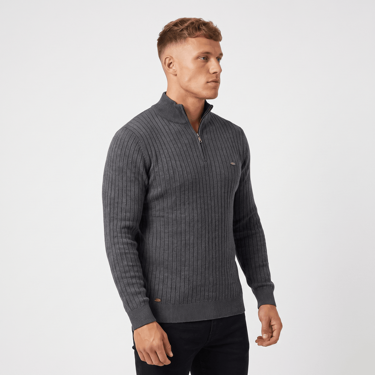Side view of a man wearing a charcoal ribbed quarter-zip sweater with a stand collar and fitted silhouette.