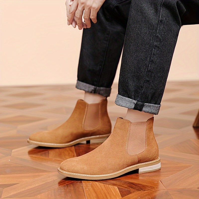 Close-up of tan suede Chelsea ankle boots worn with cuffed black jeans, showing the pale contrast sole