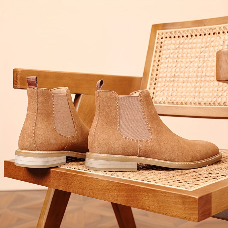 Pair of tan suede Chelsea ankle boots for men with pale contrast sole, on a wooden bench