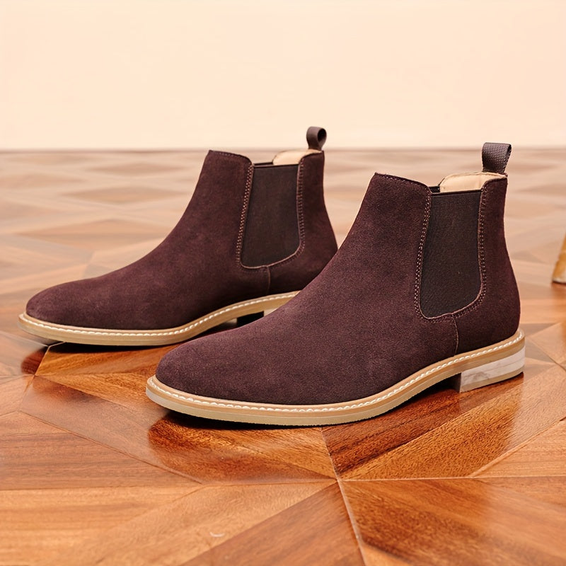 Pair of dark brown suede Chelsea ankle boots for men with pale contrast sole, on a parquet floor
