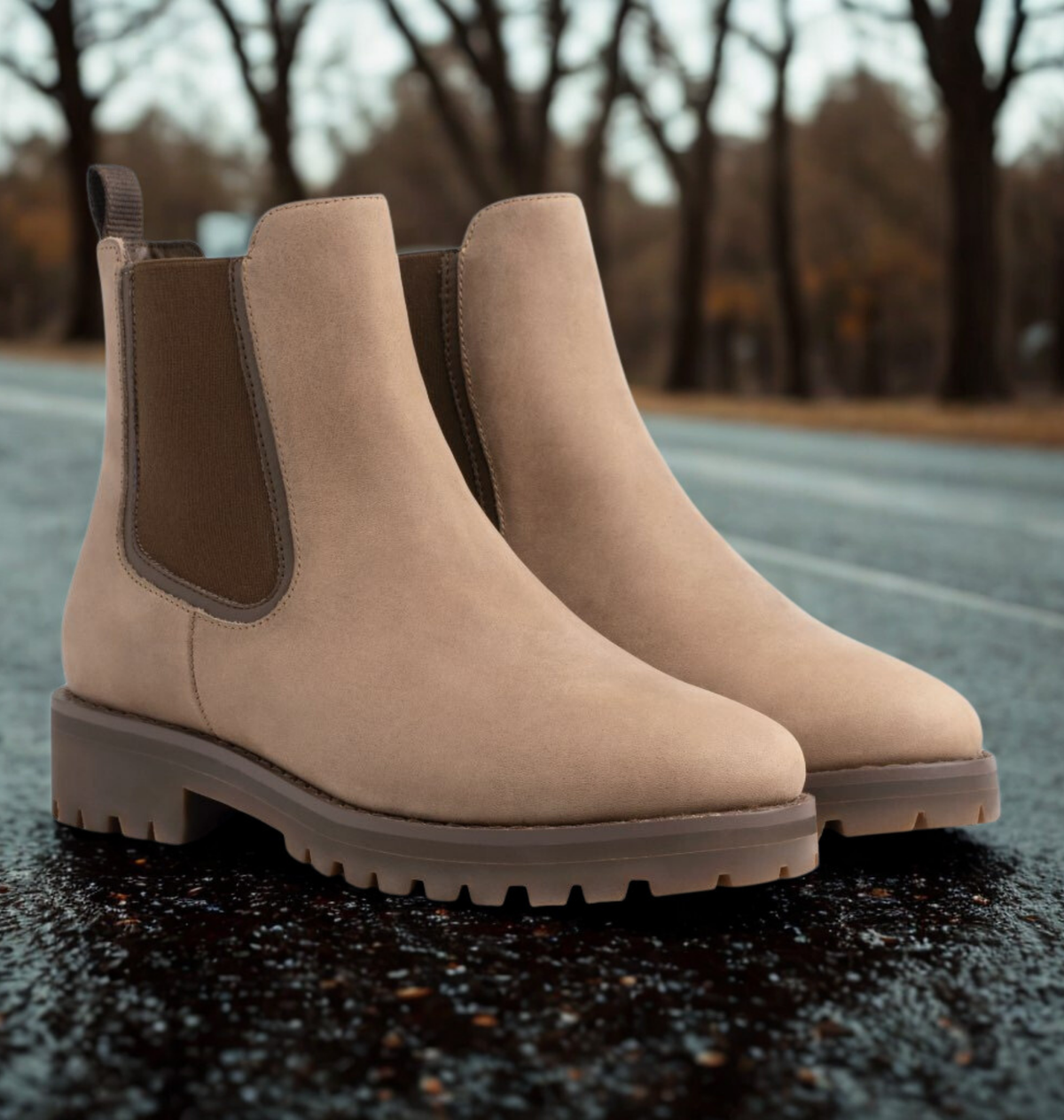 Pair of beige chunky Chelsea boots for women with elastic side panels and deep lug sole, on wet ground