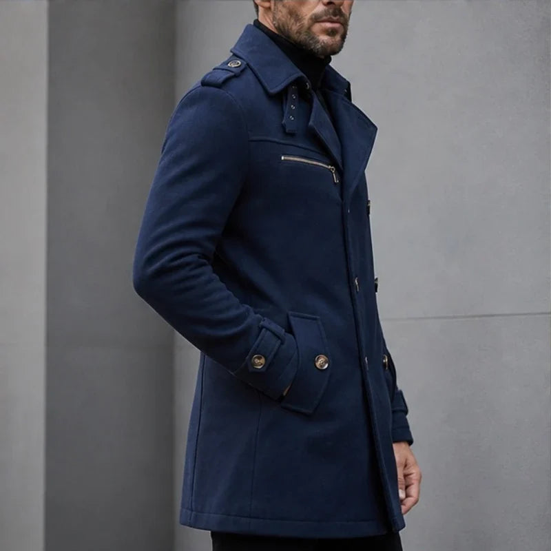A man wearing a navy blue cotton blend trench coat with a belted waist, shown in side view