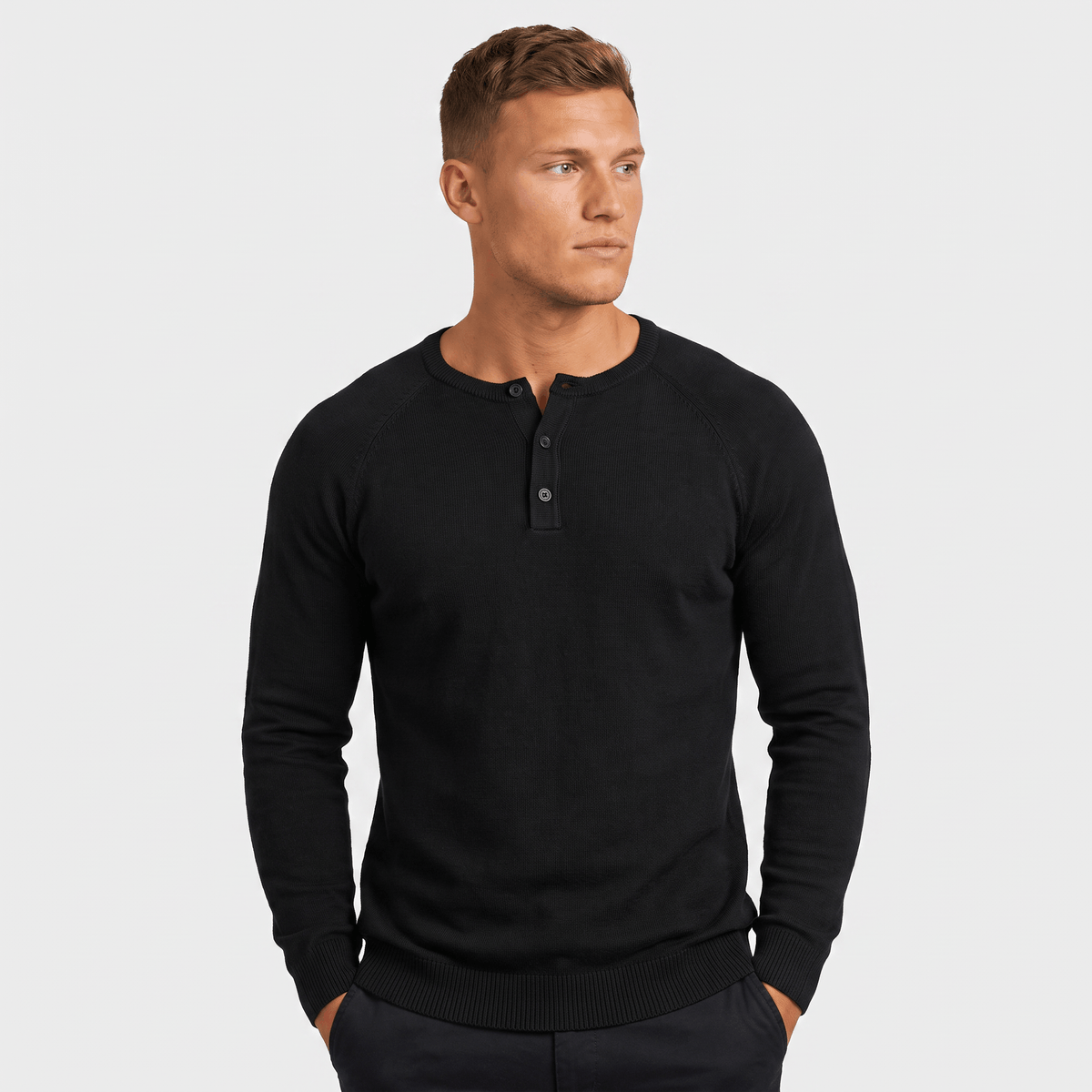 Man wearing a black waffle knit Henley sweater featuring a three-button neckline, textured knit fabric, and classic fit.