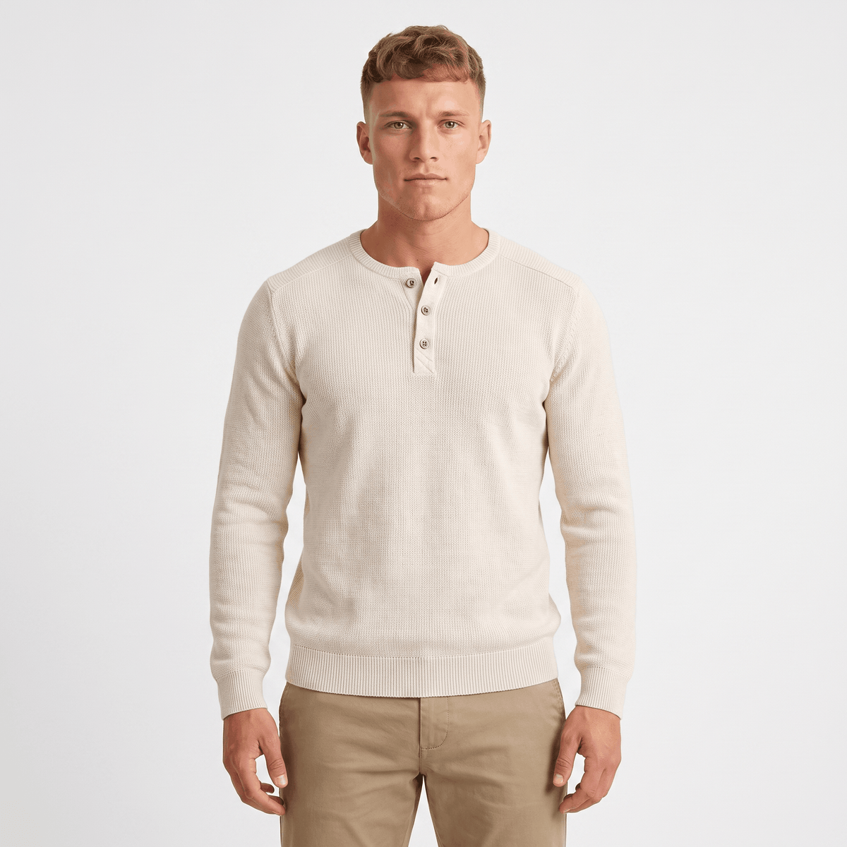 Man wearing a cream waffle knit Henley sweater with a three-button placket, ribbed cuffs, long sleeves, and a classic fit.
