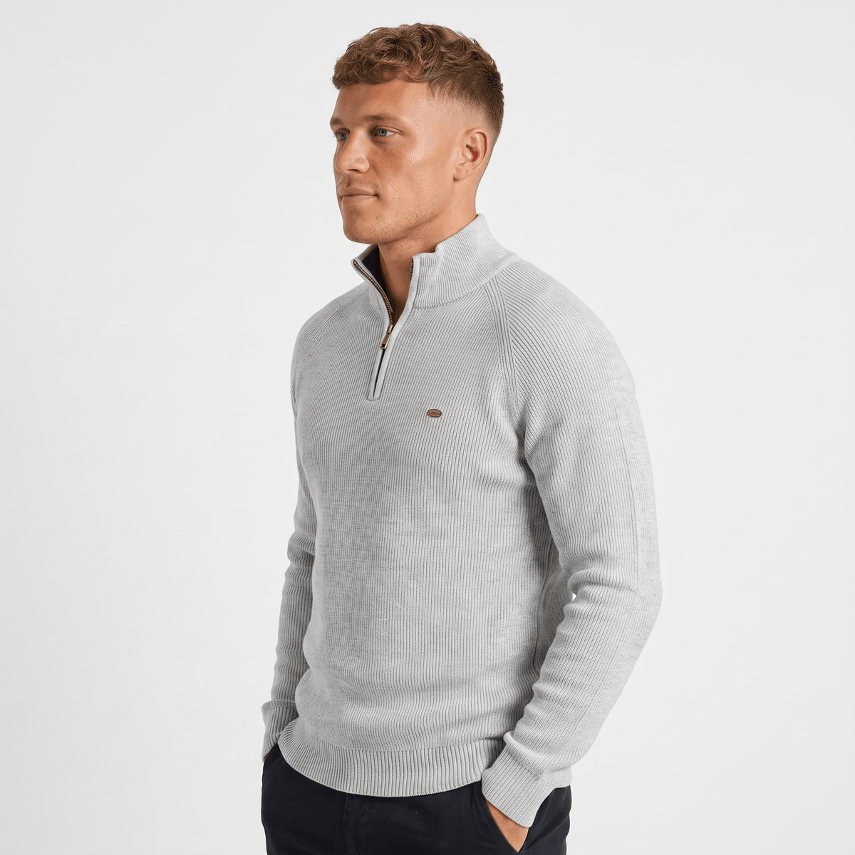 Side view of a man wearing a light gray ribbed quarter-zip sweater featuring a stand collar and fitted silhouette.