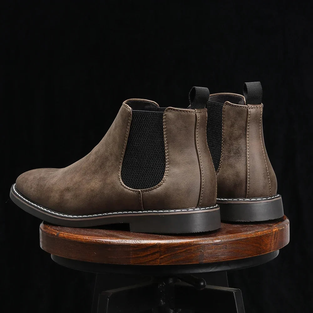 Distressed dark brown leather Chelsea boots with black elastic side panels, back pull loops, and a stitched welt sole.