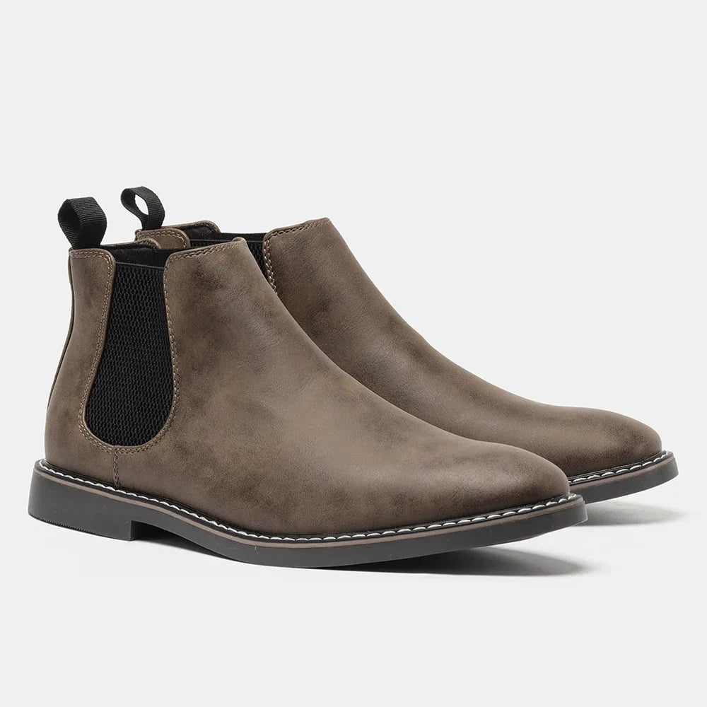 Distressed dark brown leather Chelsea boots with black elastic side panels, back pull loops, and a white stitched welt sole.