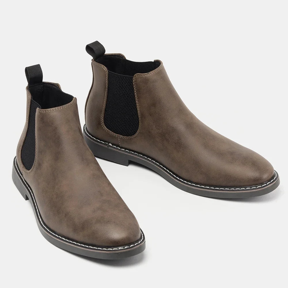 Distressed dark brown leather Chelsea boots with black elastic side panels, back pull loops, and a white stitched welt sole.