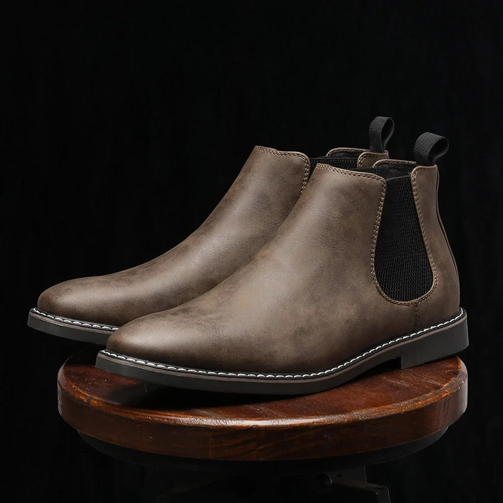 Distressed dark brown leather Chelsea boots with black elastic gore panels, back pull loops, and a white stitched welt sole.