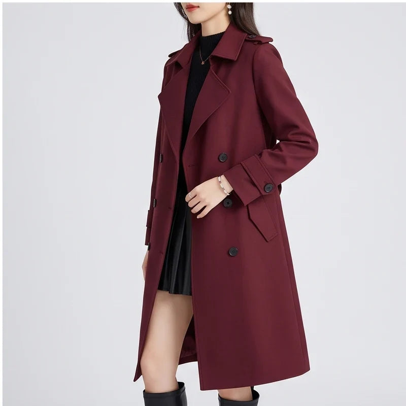 A woman wearing a burgundy double-breasted trench coat with a tailored fit and turn-down collar, shown in side view