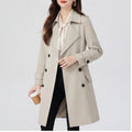 A woman wearing a cream double-breasted trench coat with a tailored fit and turn-down collar