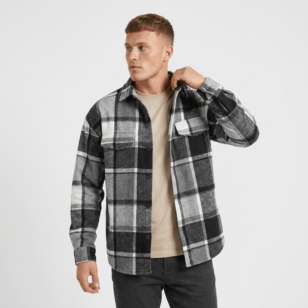 Man wearing a black and white plaid overshirt jacket with a button-front closure, chest pockets, and long sleeves over a dark shirt.