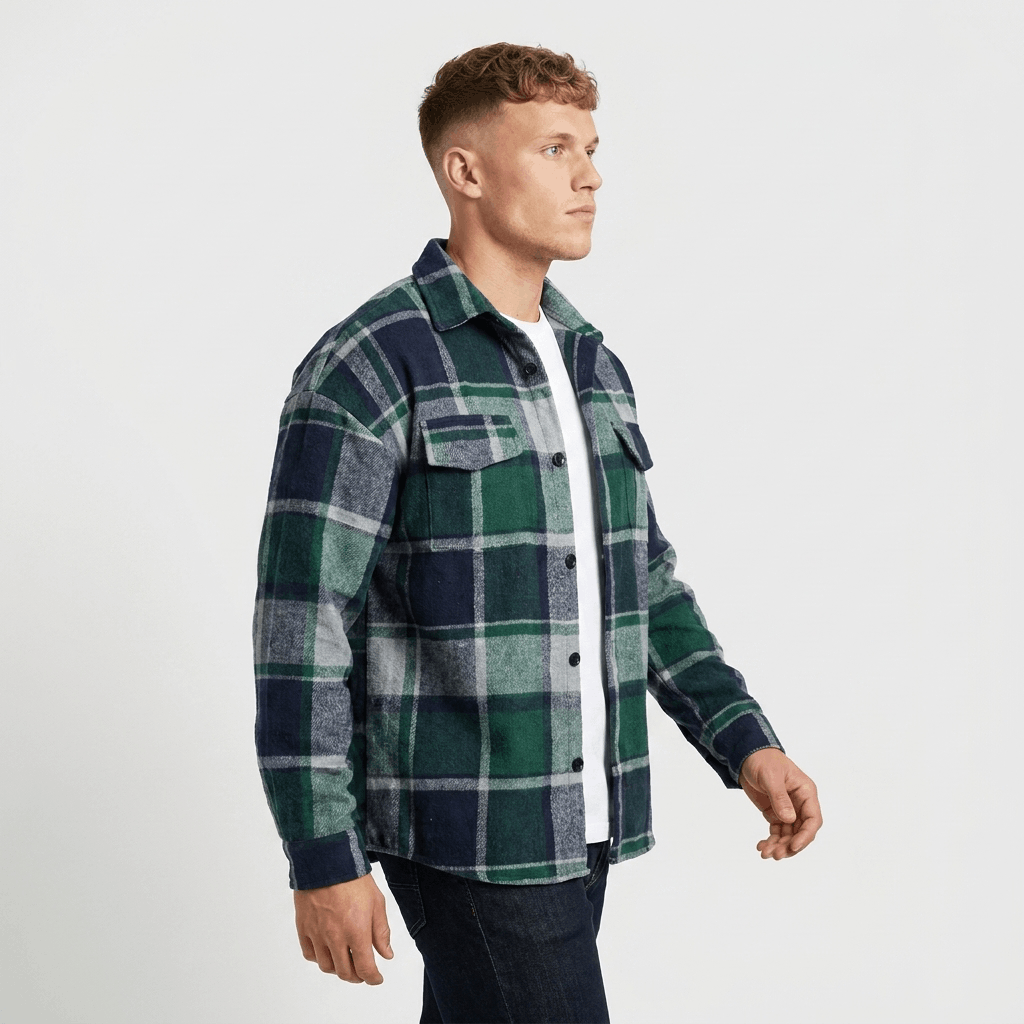 Man wearing a green, navy, and white plaid overshirt jacket with a button-front closure, chest pockets, and long sleeves.