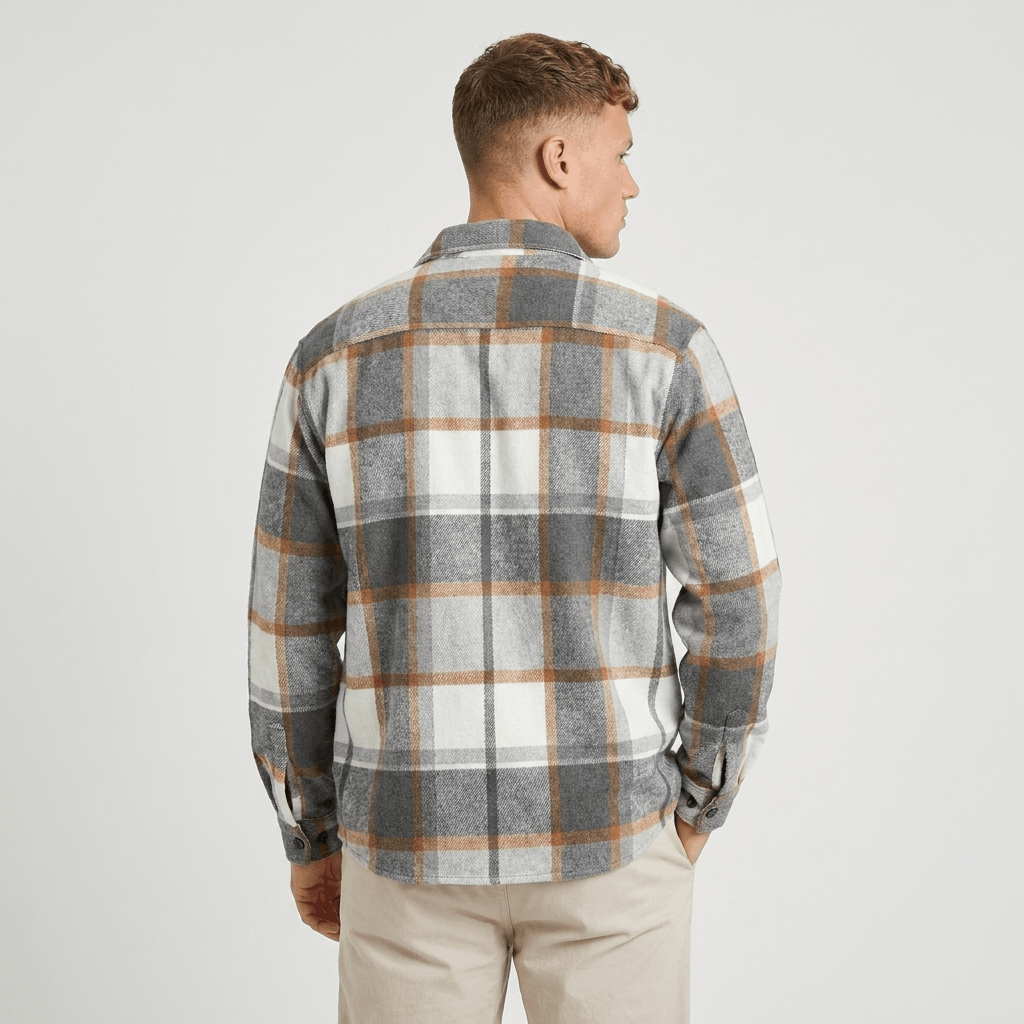 Back view of a man wearing a gray, white, and tan plaid overshirt jacket with a relaxed fit and long sleeves.