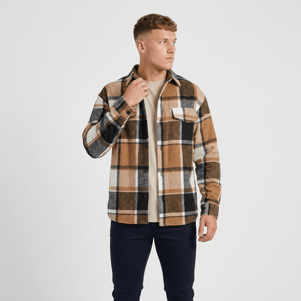 Man wearing a tan, brown, and black plaid overshirt jacket over a white shirt with dark trousers.