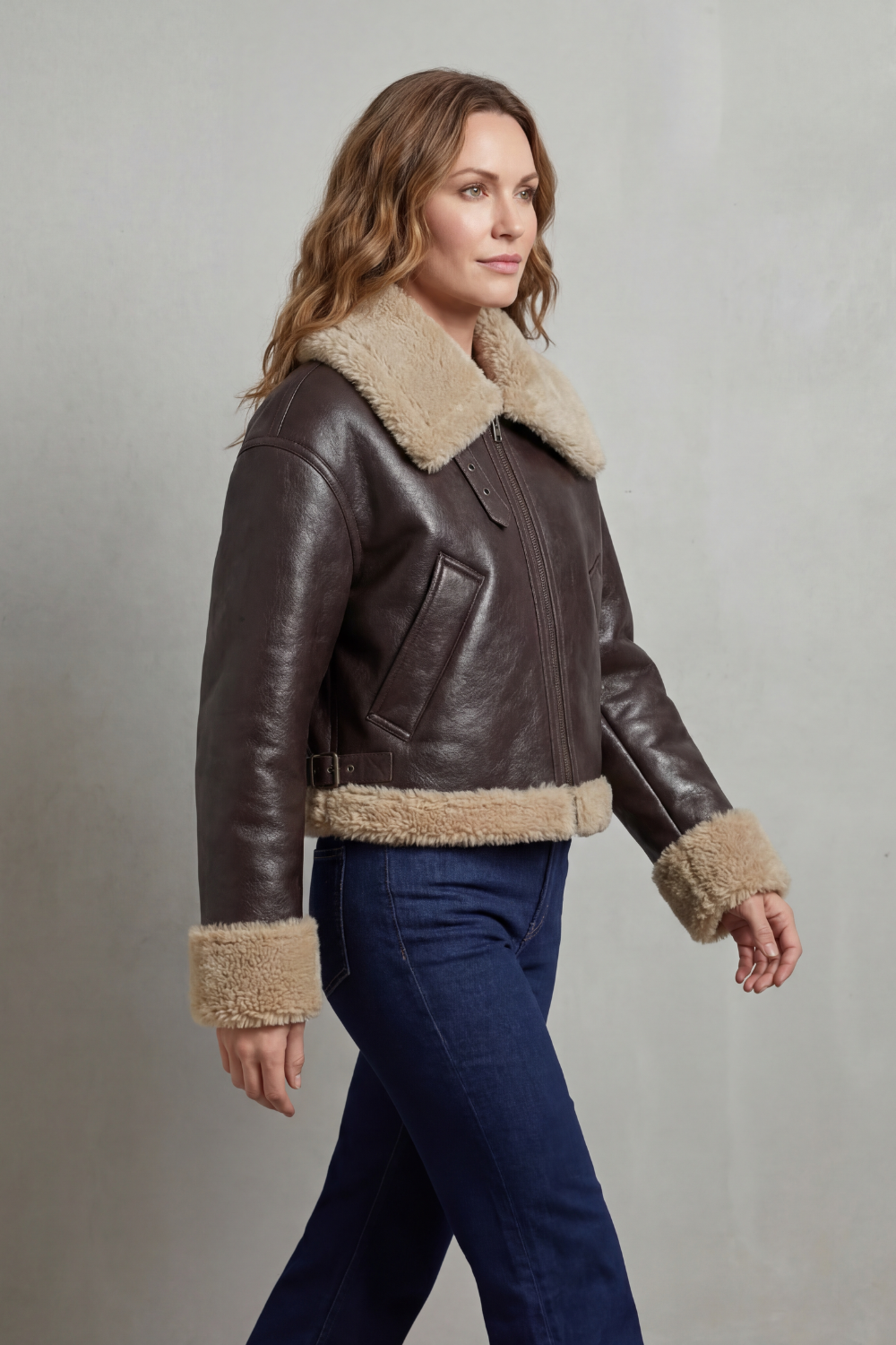 A woman wearing a cropped fleece aviator jacket with a plush shearling collar and cuffs, shown in side view