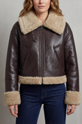 A woman wearing a cropped fleece aviator jacket with a plush shearling collar, cuffs, and waistband