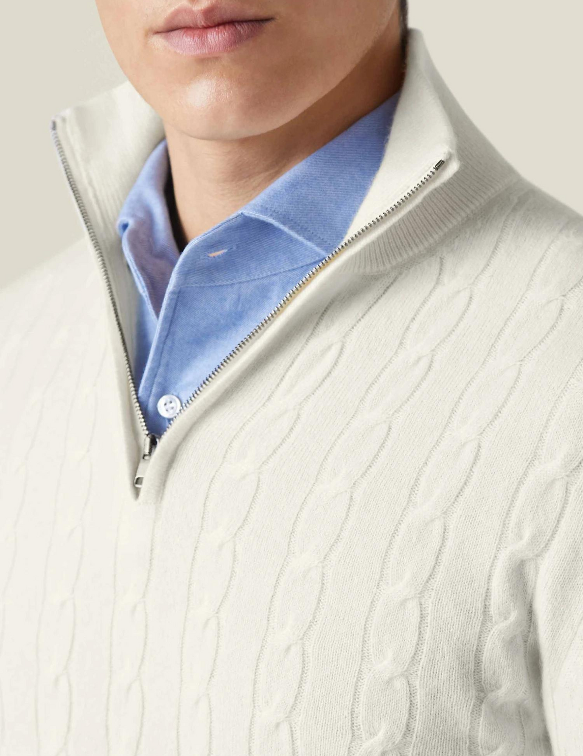 White cable knit V-neck sweater close-up showing textured knit pattern and light blue shirt collar