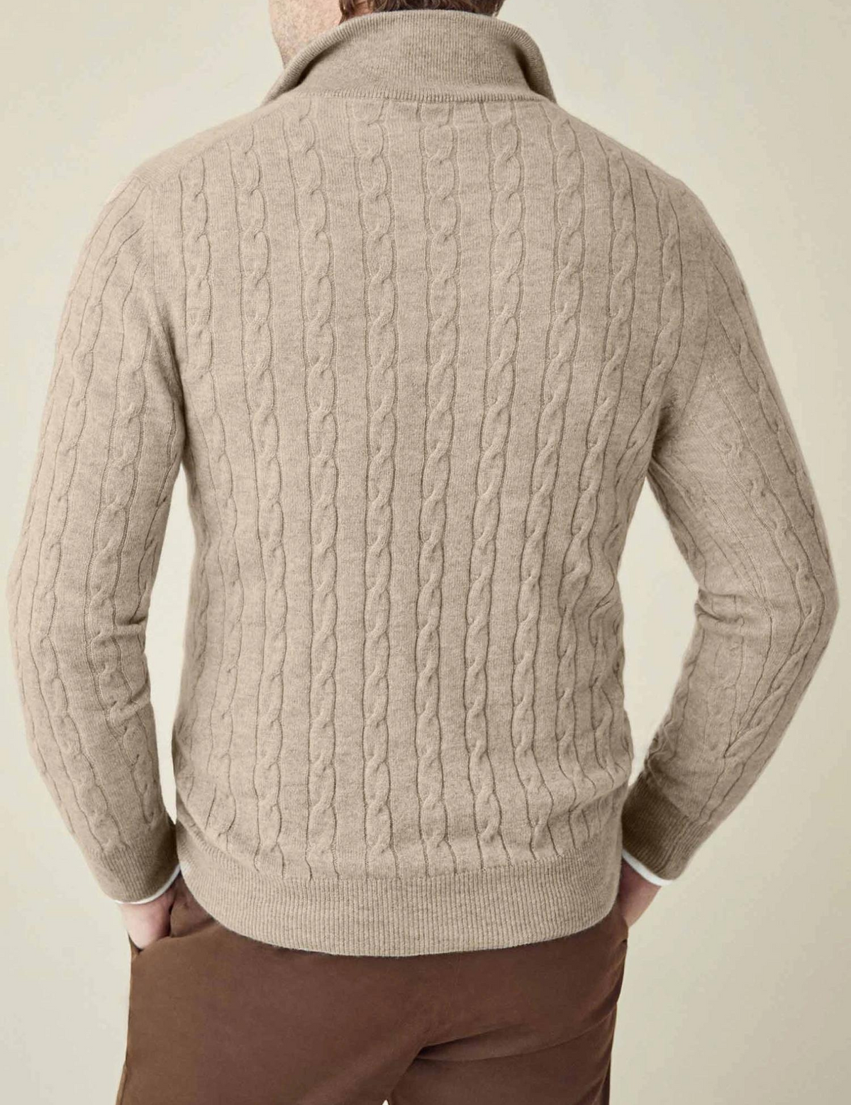 Beige cable knit V-neck sweater shown from the back with textured knit pattern and ribbed hem