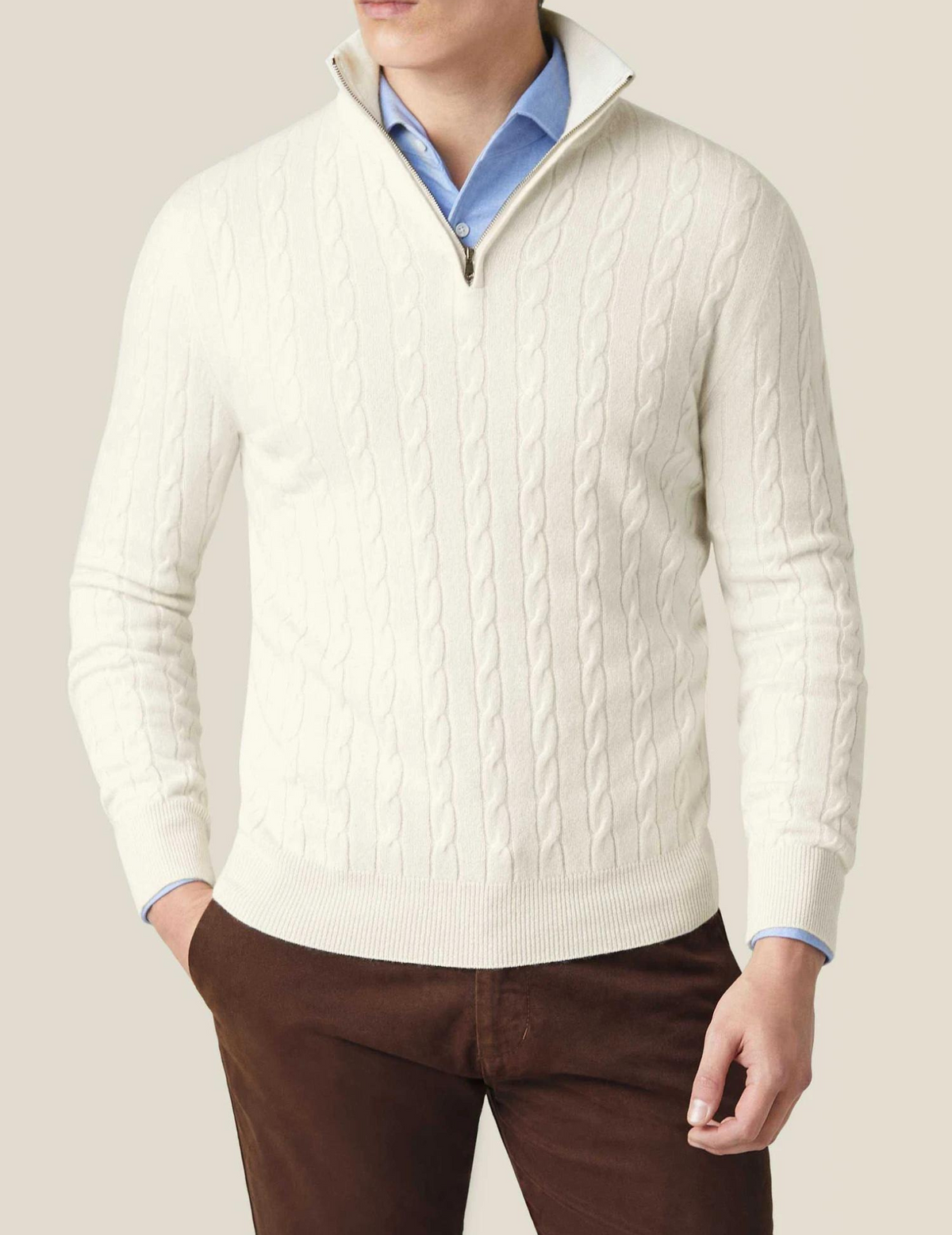 White cable knit V-neck sweater worn with a light blue collared shirt, long sleeves, and ribbed hem