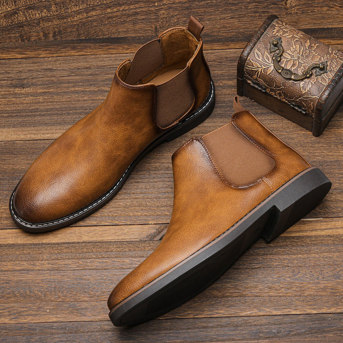 Light Brown leather Chelsea boots displayed on a wooden surface, highlighting the polished finish, elastic panels, and pull tabs.