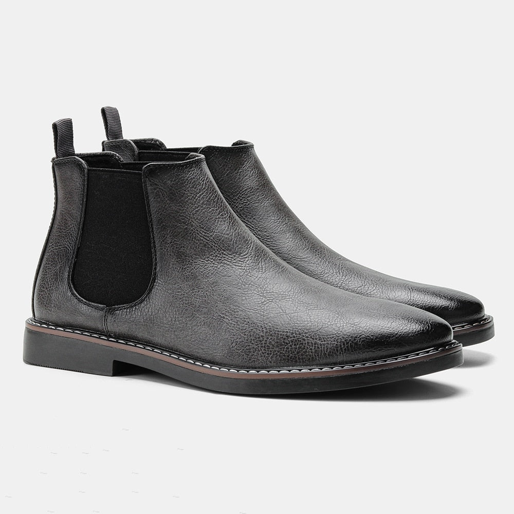 Single black leather Chelsea boot featuring an elastic side panel, rear pull tab, and low stacked sole.