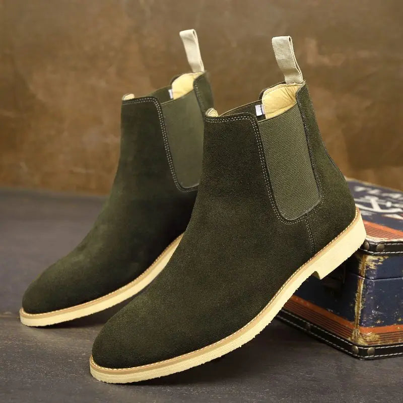 Pair of dark olive green Suede Chelsea boots with contrasting elastic side panels, rear pull tabs, rounded toes, and light-colored soles.