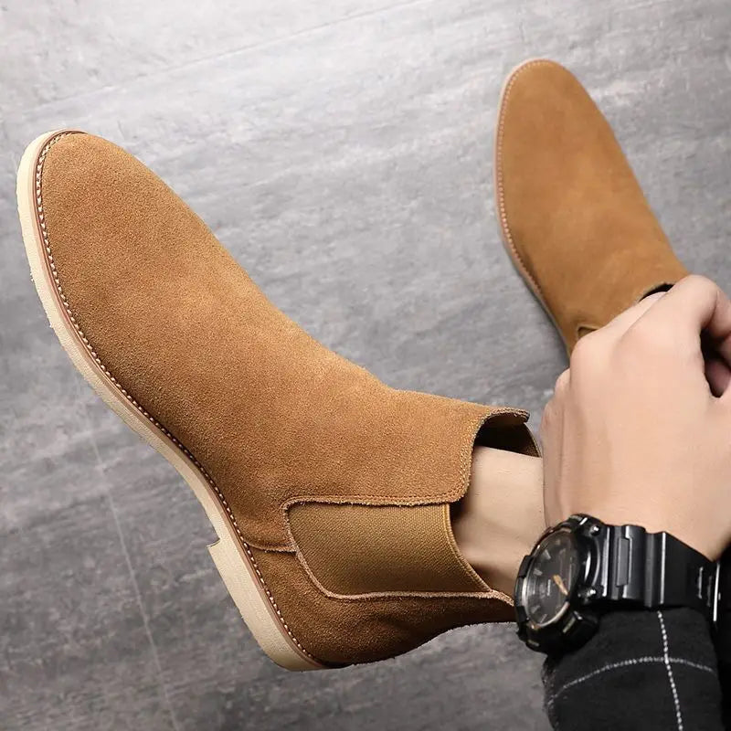 Close-up of brown suede Chelsea boots worn with rolled-up trousers, highlighting the ankle fit and elastic side panels.