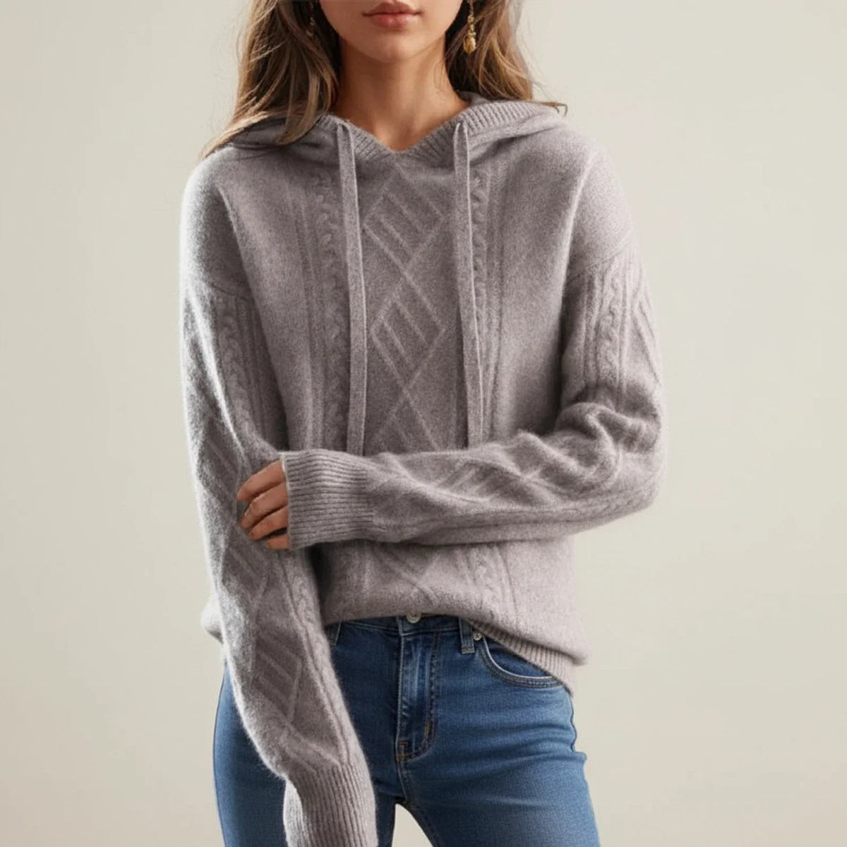 Gray hooded cable knit sweater worn by a female model, front view