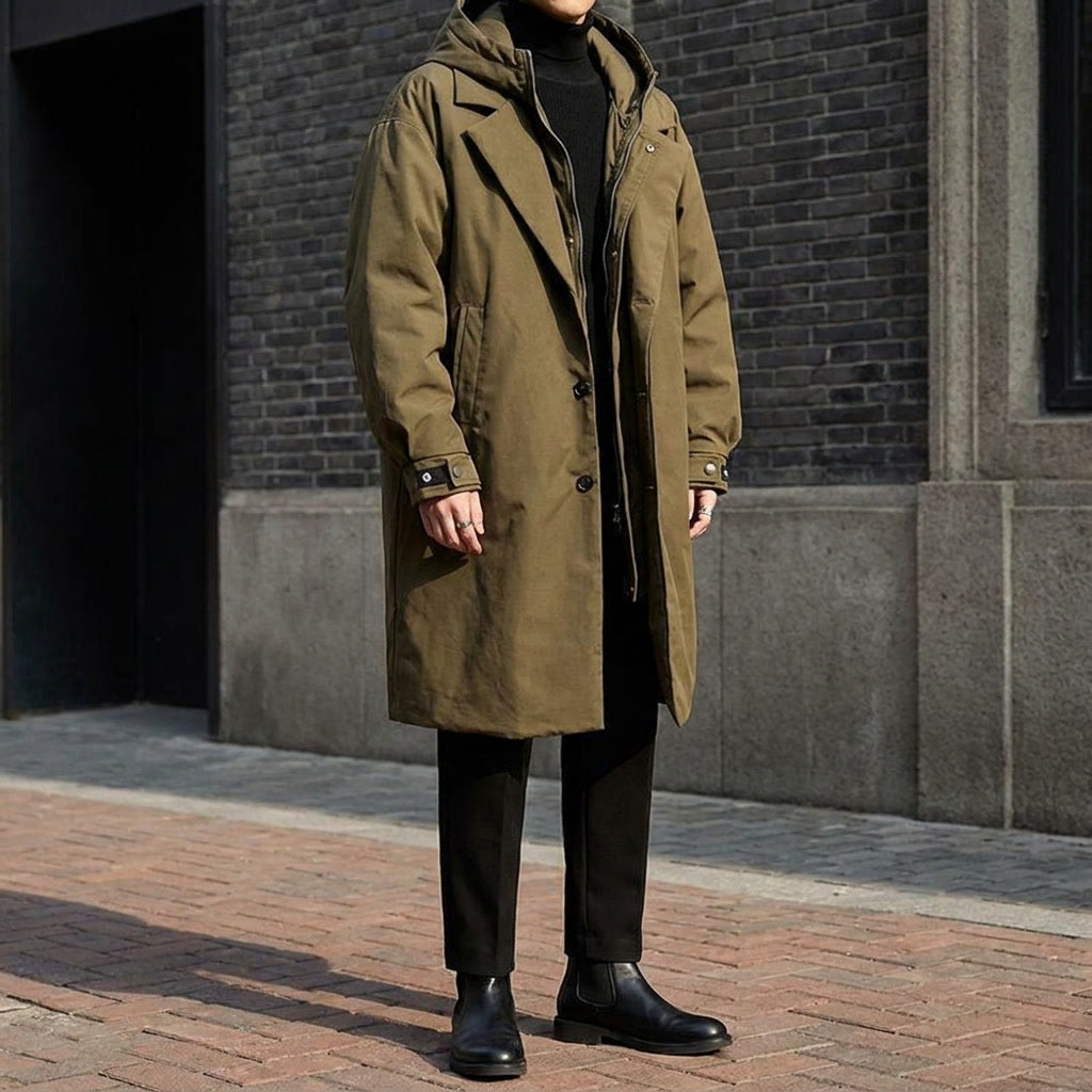 A man wearing a khaki hooded tailored overcoat with a longline fit, shown outdoors