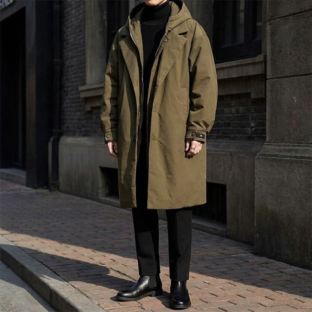 A man wearing a khaki hooded tailored overcoat with a longline fit, standing outdoors
