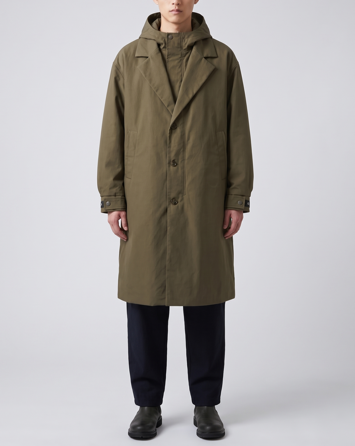 A man wearing a khaki hooded tailored overcoat with a water-resistant shell and longline fit