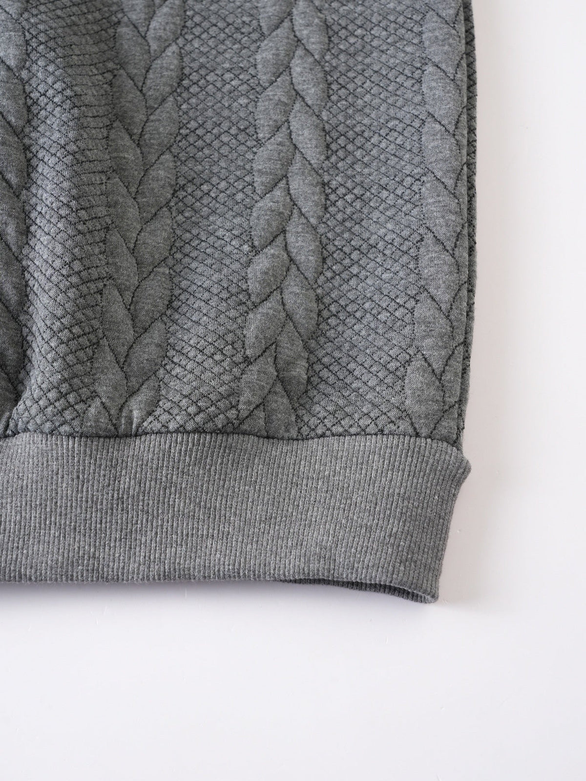 Gray cable knit quarter-zip sweater close-up showing front zipper and textured knit detailing