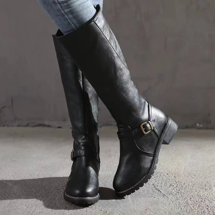 Black smooth grain knee-high riding boots featuring a round toe, low stacked block heel, and an ankle buckle strap.