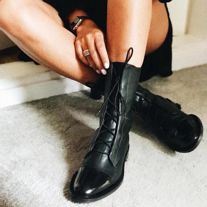 Person adjusting the laces of black leather ankle boots.