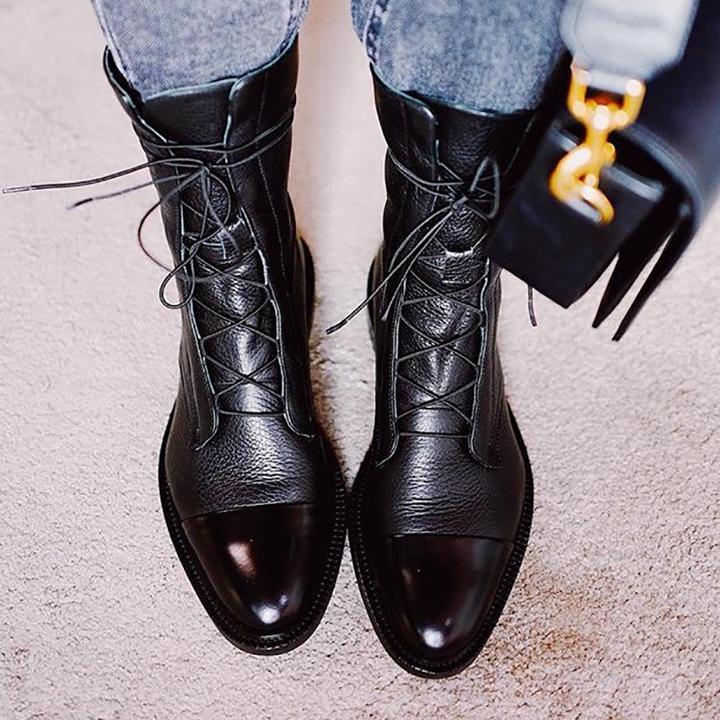 Black leather lace-up ankle boots worn with blue jeans.