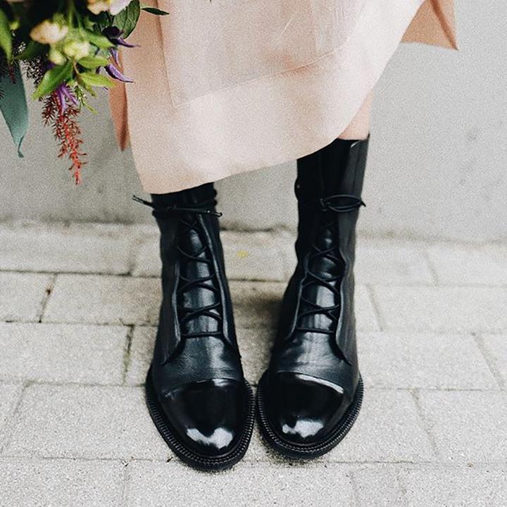 Black leather lace-up boots worn with light pink pants.